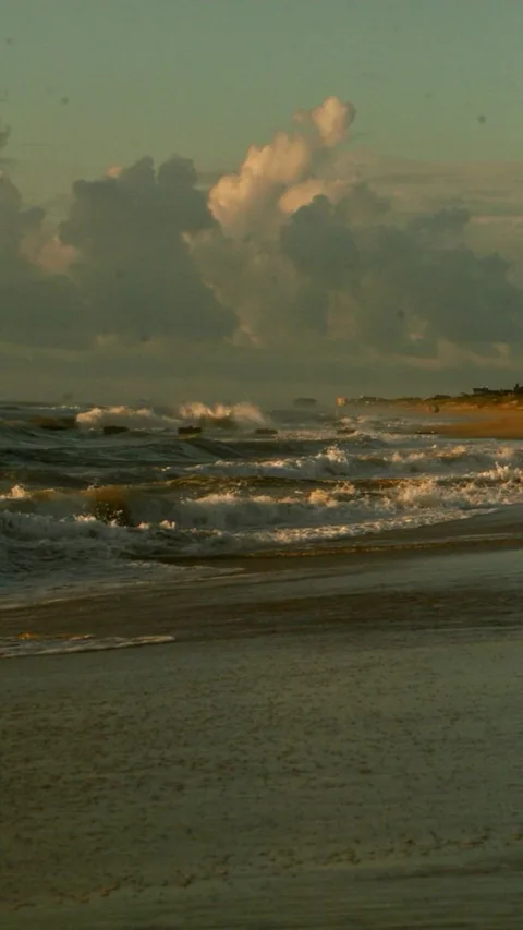 Waves breaking on a beach in warm evening light.